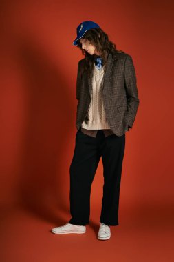 Çekici genç adam, çarpıcı bir kırmızı zemine karşı kendine güvenen modaya uygun bir şekilde poz veriyor..