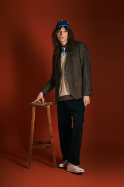 Şık bir genç adam kendine güvenerek duruyor, kırmızıya karşı modaya uygun bakışlarıyla gözlerini alıyor..