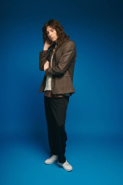 Şık giyinmiş yakışıklı bir genç, şık bir stüdyo ortamında dengeli bir poz veriyor..