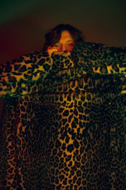 Cesurca giyinmiş genç bir adam şık ve eşsiz bir stil sunar. Leopar desenli bir paltoya sarılı..