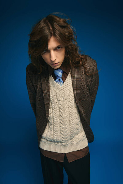 Стильный молодой человек уверенно демонстрирует свой шикарный наряд на ярко-голубом фоне.