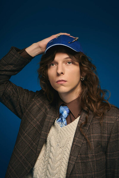 Шикарный молодой человек уверенно позирует, смешивая современные и винтажные стили в поразительном наряде.