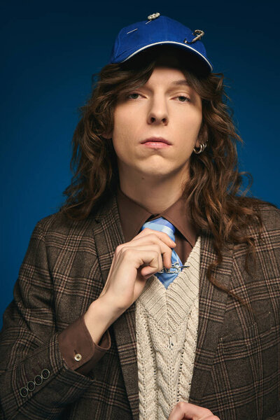 Уверенный молодой человек, одетый в стильный наряд, регулирует галстук, источая очарование и харизму..