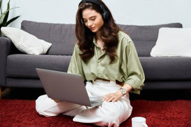 Bright and focused, a young woman sits on the floor engaging with her laptop, learning remotely. clipart