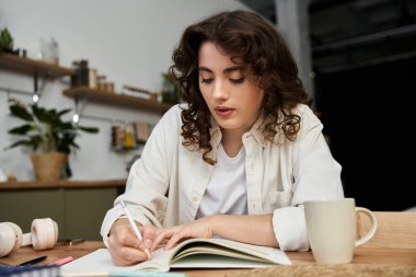 Sıcak ve davetkar bir yerde, genç bir kadın masasında otururken notlar alır..