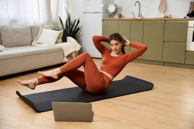 Egzersizine odaklanan genç bir kadın, rahat bir ev ortamında spor yolculuğunu geliştirir..