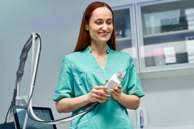 Genç ve güzel bir dermatolog cilt tedavisi için hazırlanırken gülümsüyor..