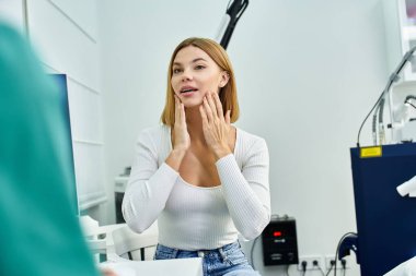 Dermatoloğuyla cilt bakımı yaptıran şık giyinmiş genç bir kadın..