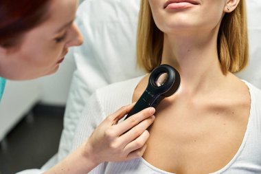 Yetenekli bir profesyonel, bilgilendirici bir dermatoloji seansı sırasında genç bir kadının cildini inceler..