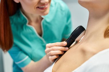 Yetenekli bir dermatolog modern bir klinikte hastaların derilerini büyüteç ile muayene eder..