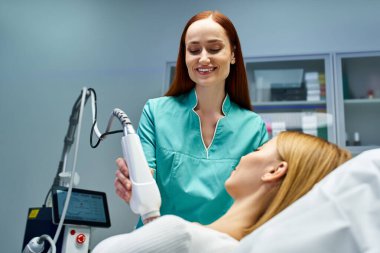 Yetenekli bir dermatolog, klinik ortamında genç bir kadına cilt ameliyatı yapıyor..