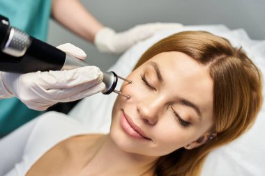 Genç bir kadın, sakinleştirici bir dermatoloji kliniğindeki yetenekli bir doktordan cilt bakımı alır..