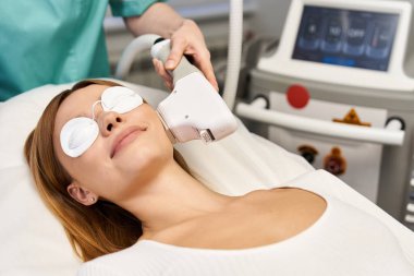 Genç bir kadın modern bir dermatoloji kliniğinde cilt bakımı görüyor ve güzelliğini arttırıyor..