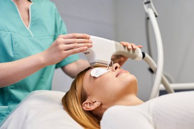 Yetenekli bir pratisyen, güzelliğini geliştirmeye odaklanmış genç bir kadın üzerinde deri tedavisi uygular..