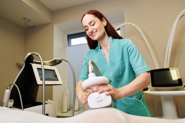 Genç ve yetenekli bir dermatolog, bir müşterisine cilt bakımı yaparken gülümser..