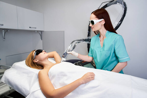 A skilled practitioner performs laser hair removal on a patient in a sleek clinic environment.