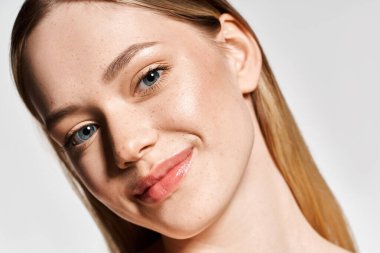 Uzun saçlı ve kusursuz ciltli güzel bir kadın zarif bir şekilde gösteriş yaparken sıcacık gülümsüyor..