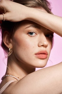 Genç bir kadın, zahmetsiz cazibe ve tarz saçan pastel bir arka plana nazikçe poz verir..