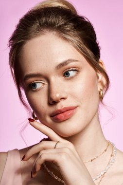 Güzel bir kadın düşünceli bir şekilde poz verir. Şık kıyafetleri gençlik zarafetini ve çekiciliğini ön plana çıkarır..