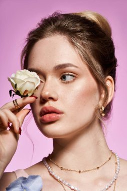Zarif görünümlü genç bir kadın beyaz bir gül tutuyor, güzelliğini ve tarzını gösteriyor..