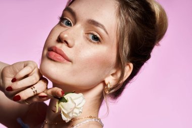 Zarif genç bir kadın beyaz bir gül ile zarif poz verir, bahar kıyafetine güveni yayar..