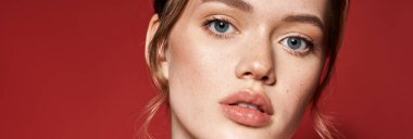 Genç bir kadın zarif tarzını canlı kırmızı bir arka plana karşı sergiliyor..