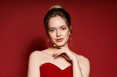 Çekici kadın zarif bir şekilde poz veriyor, güzelliğini ve şıklığını kırmızı bir ortamda sergiliyor..
