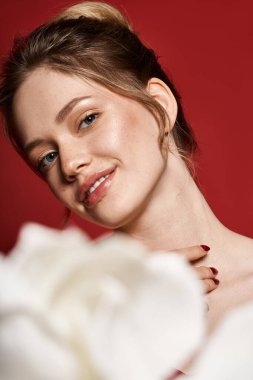 Güzel genç bir kadın zarif bir şekilde gülümsüyor, zarif görünüşünü sergiliyor. Yumuşak çiçeklerin arasında..