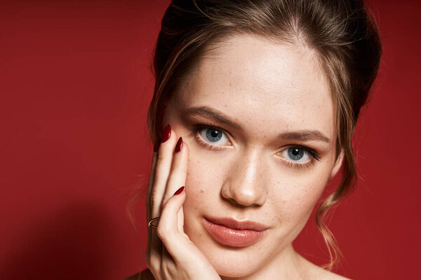 Излучая красоту, женщина подчеркивает свой стиль с деликатным прикосновением на ярком красном фоне.