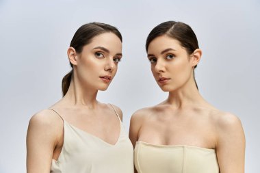 İki güzel kız kardeş yan yana poz verir. Sakin bir ortamda zarafet ve zarafet yayarlar..