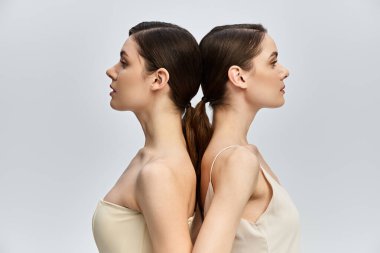 İki güzel ikiz kardeş sırt sırta dururlar, zarafet ve aile bağlarını somutlaştırırlar..