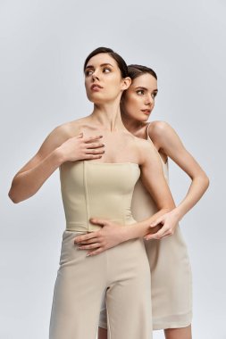 İki güzel ikiz kardeş zarifçe poz veriyor, zarafetlerini ve bağlarını sergiliyorlar..