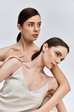 İki güzel kız kardeş zarif bir şekilde poz veriyor, çarpıcı özelliklerini ve yakın bağlarını sergiliyorlar..