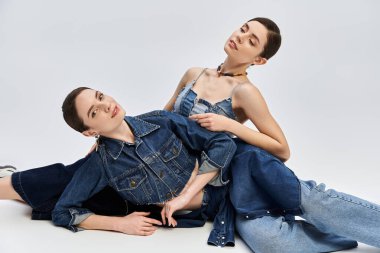 İki güzel ikiz kardeş şık kot giysiler içinde zarifçe poz veriyor. Cazibeli ve zarif..