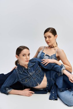 Two beautiful sisters pose gracefully in trendy denim outfits, exuding elegance and style. clipart