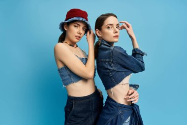 İki güzel kız kardeş şık bir kot giyip özgüvenle poz veriyorlar.