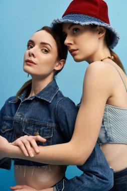 İki güzel kız kardeş birlikte poz veriyor, gösteriş tarzı ve zarafeti parlak bir arkaplana karşı..