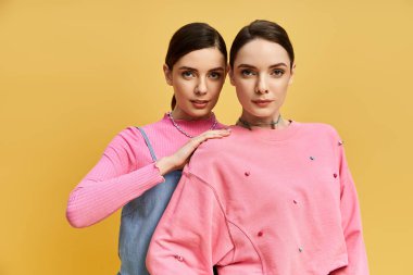 İkiz kardeşler benzersiz tarzlarını, parlak sarı bir arka planda sergiliyorlar..