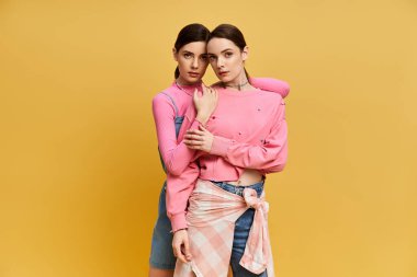 İki güzel ikiz kardeş, neşe saçan parlak giysiler içinde sıcak bir anı paylaşıyorlar..