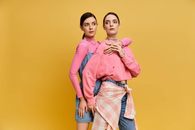 İki şık ikiz kardeş güneşin altında şakacı bir bağ paylaşıyor..