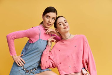 İki güzel kız kardeş şık giysiler içinde birlikte poz verirler. Bu onların neşeli kişiliklerini yansıtır..