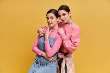 İki güzel kız kardeş rengarenk kıyafetler giyip, neşe saçarak poz verirler..