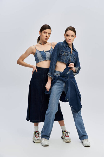 Twins express their individuality through trendy denim outfits, striking playful poses together
