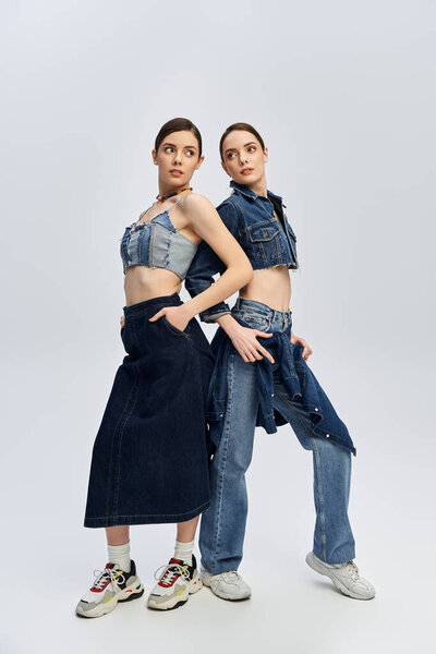 Two beautiful twins stand confidently, modeling stylish denim outfits with charm and elegance.
