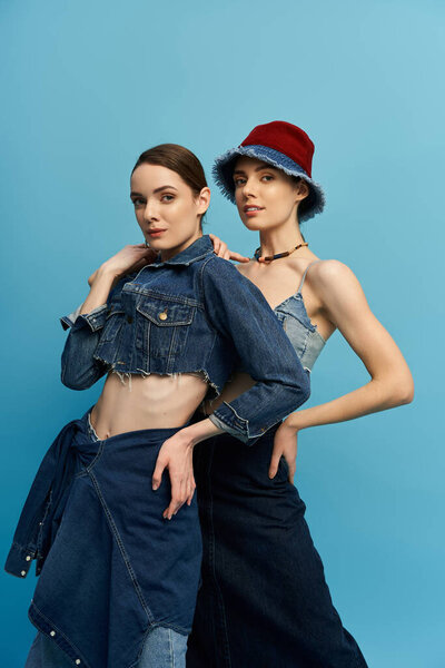 Two pretty twin sisters shine in fashionable denim, showing their unique individual styles together.