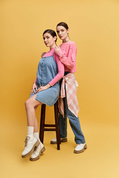 Two pretty sisters stand confidently, showcasing their stylish outfits and strong bond.