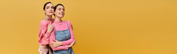 Two pretty sisters share a joyful moment while posing in stylish outfits, radiating happiness.