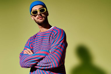 Şık bir genç adam eşsiz moda anlayışını parlak yeşil bir arka planda sergiliyor..