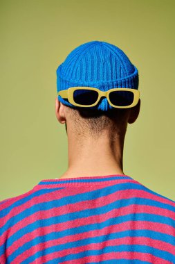 Yakışıklı genç bir adam modaya uygun bir kıyafetle stüdyoda benzersiz moda anlayışını ön plana çıkarıyor..