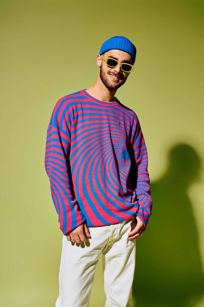 Handsome young man showcases a trendy outfit with vibrant sunglasses in a studio setting.